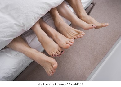 Low section of woman with two men in bed