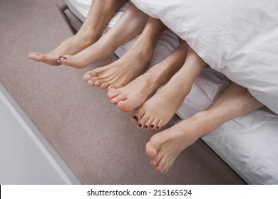 Low Section Of Woman With Two Men In Bed