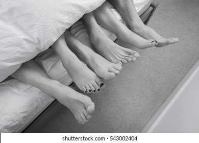 Low section of woman with two men in bed