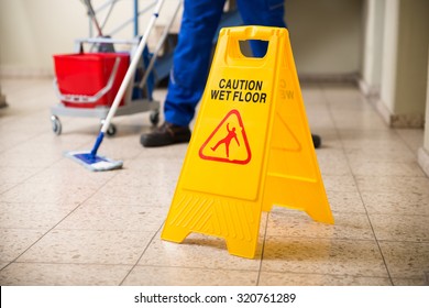 Low Section Of Worker Mopping Floor With Wet Floor Caution Sign On Floor - Shutterstock ID 320761289