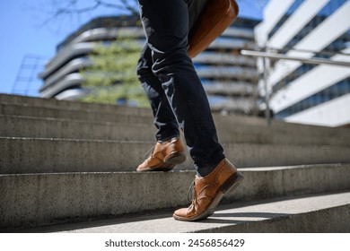 Low section of young businessman wearing leather shoes walking on steps against building in city - Powered by Shutterstock