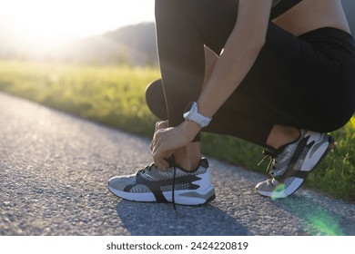 Low section of a young woman tying her running shoes before training - Powered by Shutterstock