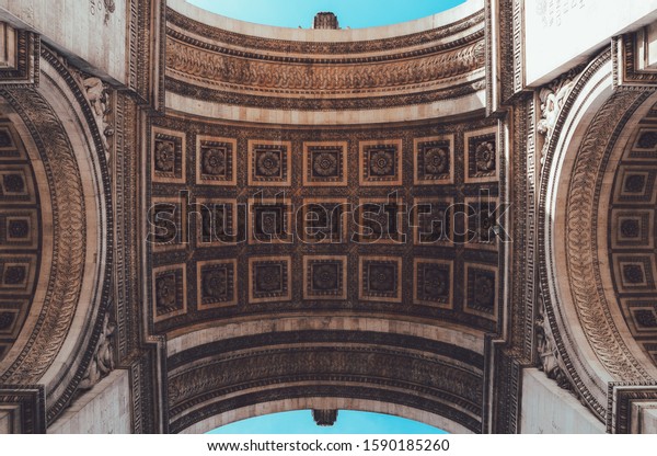 A low shot of a ceiling of the Arc of\
Triumph in Paris with beautiful engravings on\
it