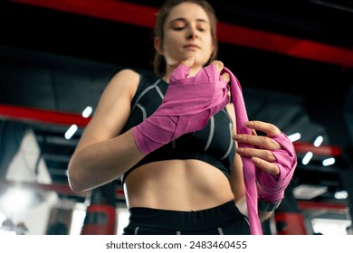 low shot close up at a boxing fight club young girl in a black sweatshirt wraps pink elastic bandages for boxing around her hands preparing for training - Powered by Shutterstock