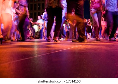 A low shot of the dance floor with people dancing under the colorful lights.