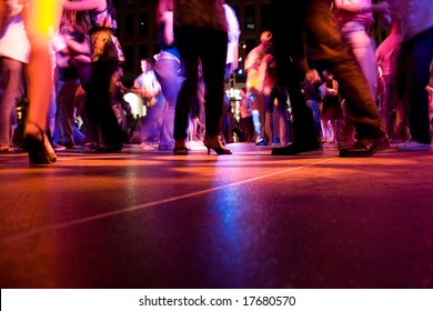 A low shot of the dance floor with people dancing under the colorful lights