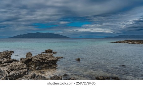 Low tide. Clams can be seen attached to exposed boulders. Calm turquoise ocean, clear water. Mountains on the horizon. Blue sky, clouds. Madagascar. Nosy Tanikeli      - Powered by Shutterstock - Get 15% off with code: PIKWIZARD15