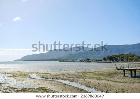 Low tide on a fine, sunny day at Cairns Esplanade: mud flats in the foreground, and hills in the distance — Coral Sea, Cairns; Far North Queensland, Australia