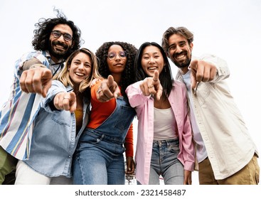 Low view of cheerful multiracial group of young hipsters pointing and looking at camera. Happy diverse group of young hipsters staring at camera outside and pointing fingers at the camera. - Shutterstock ID 2321458487