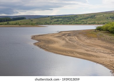 Low water level on a UK reservoir. Fly fishing in drought conditions. Water shortage during summer.