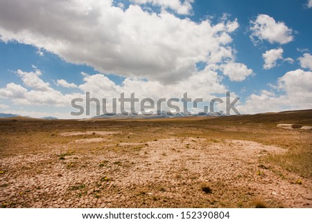 Low white clouds floating over dry land of the mountain plateau in Central Asia