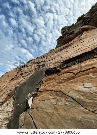 Low-angle abstract of sharp, angular rock formations pointing towards a dramatic cloudy sky. Highlights severe textures and leading lines in nature