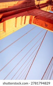 A low-angle, architectural view of a tower on the Golden Gate Bridge in San Francisco. The bridge is famous for its distinctive reddish-orange color, officially known as International Orange. 