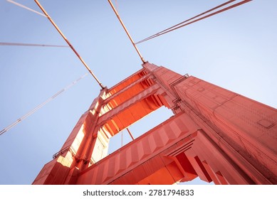 A low-angle, architectural view of a tower on the Golden Gate Bridge in San Francisco. The bridge is famous for its distinctive reddish-orange color, officially known as International Orange. 