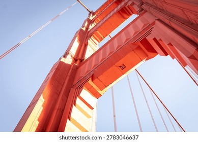 A low-angle, architectural view of a tower on the Golden Gate Bridge in San Francisco. The bridge is famous for its distinctive reddish-orange color, officially known as International Orange. 