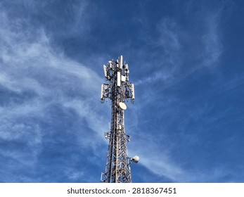 Low-angle cell tower standing tall against deep blue dramatic sky