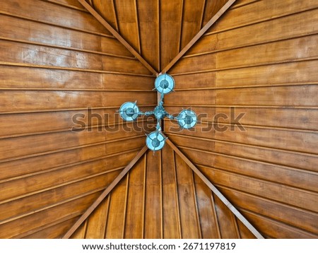 A low-angle, centered shot of a wooden ceiling with a light fixture hanging in the middle.