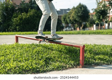 low-angle close-up image showcases the legs of a skater as they execute a grind on a striking red rail in the skate park. emphasizes the intensity of the trick capturing the skater's skill and control - Powered by Shutterstock