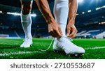 A low-angle, close-up view captures the intense moment a soccer player adjusts the white laces on his cleat, preparing for intense competition on the vibrant green pitch.
