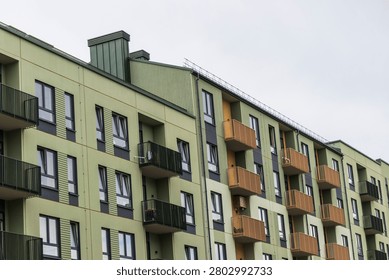 Low-angle diagonal view of a modern multi-colored apartment building row featuring green facades and bright yellow geometric balconies.