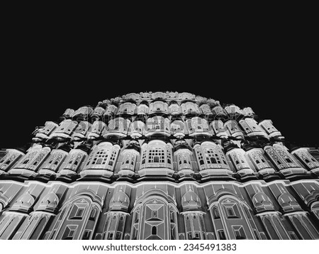 A low-angle grayscale of the Hawa Mahal Palace in Jaipur India with unique sandstone architecture