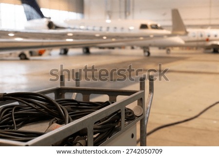 Lowangle gulfstream g engine and wing with ground cart and cable foreground, operational hangar prep for departure, power hookup and technician workflow implied