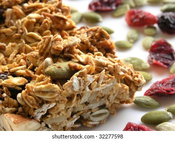 Low-angle Macro Shot Of A Breakfast Granola Bar On A White Plate Sprinkled With Pumpkin Seeds And Dried Cranberries