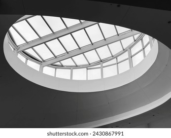 Low-angle partial view of a round geometric skylight under a white daytime sky, in black and white, for motifs of design, architecture, and illumination