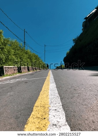 Low-angle perspective of an empty asphalt road with yellow centerline leading toward the horizon.