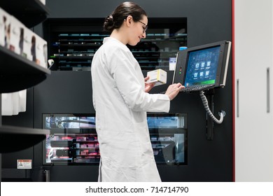 Low-angle Rear View Of An Experienced Female Pharmacist Using A Computer While Managing The Drug Stock In A Contemporary Pharmacy With Modern Technology