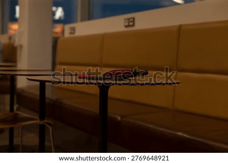 Lowangle shot of bench and table with wallet and phone, interior objects perspective emphasizes foreground details, warm upholstery and shallow depth create intimate everyday