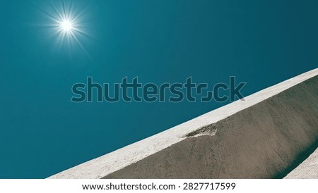 A low-angle shot captures the sun's rays illuminating a stark, modern building against a vibrant, cloudless blue sky.
