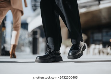 A low-angle shot capturing the fashionable shoes of two individuals walking past each other in an urban setting, illustrating movement and city life. - Powered by Shutterstock