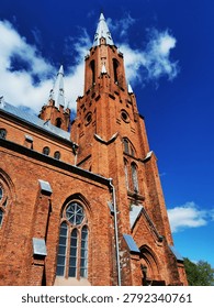 A low-angle shot capturing the imposing height and intricate detail of a neo-gothic brick cathedral, emphasizing its architectural scale and historical significance.