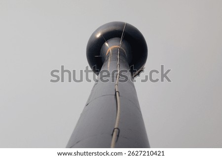 Low-angle shot capturing the underside of a water storage tank set in a rural agricultural field, highlighting infrastructure and farming environment.