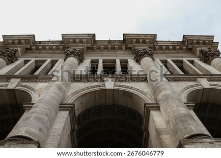 A low-angle shot of a classical building facade with rows of intricate Corinthian columns and arches.