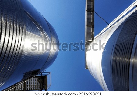 A low-angle shot of huge stainless steel tanks in an industrial center