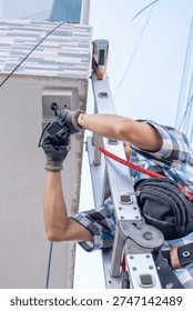 Low-angle shot of a security technician installing exterior surveillance.