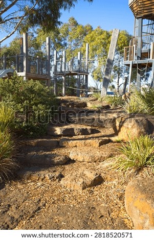 Low-angle vertical view of natural stone steps and rock landscaping leading up to the timber play structure and rope bridge at Bullion Park in Woodlea Estate, Aintree.
