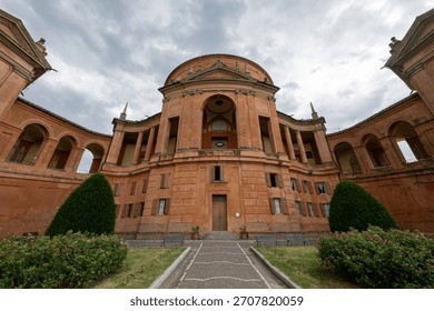 Low-angle view of the Baroque brick facade of the Sanctuary of Our Lady of San Luca on Colle della Guardia in Bologna.