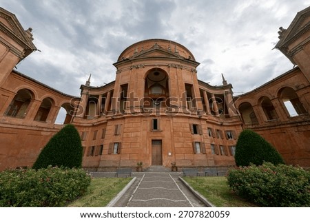 Low-angle view of the Baroque brick facade of the Sanctuary of Our Lady of San Luca on Colle della Guardia in Bologna.