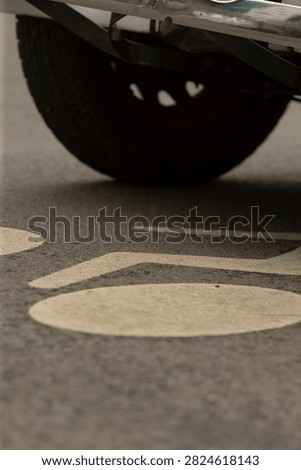 Low-angle view beneath the rear of a parked vehicle showing the tire, bumper underside and suspension components hovering above a textured asphalt surface