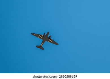 Low-angle view of a classic twin-engine airplane silhouetted against a bright cloudless sky, ideal for aviation and travel themes.