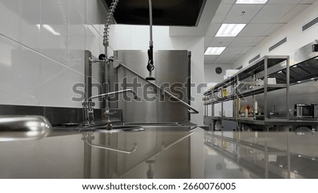 Low-angle view of a clean stainless kitchen in commercial setting, with reflective counter surface ideal for product mockups or food service visuals.
