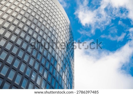 Low-angle view of a contemporary skyscraper facade with a geometric grid pattern reflecting the sky. Concept of modern architecture, business growth, and urban development.