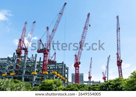 Low-angle view of cranes and steel structures of building construction with a blue sky background in Taiwan.
