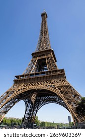 Low-angle view of the Eiffel Tower against a vibrant blue sky.  Intricate metalwork details are sharply defined.  The mood is majestic and awe-inspiring. 
