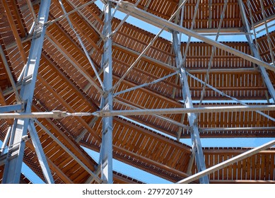 Low-angle view inside observation tower with wooden platforms, metal beams and railings against blue sky. Concept of travel architecture, viewpoint and hiking destination.