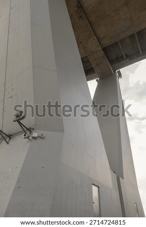 A low-angle view a large angular concrete support column of the Bhumibol Bridge (Industrial Ring Road Bridge), The imposing height and geometric forms of the bridge with sharp lines and varying shades