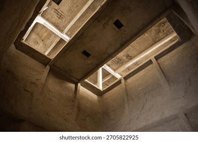 Low-angle view looking up inside a tall, abandoned cement factory silo, highlighting the brutalist concrete architecture and skylight openings.